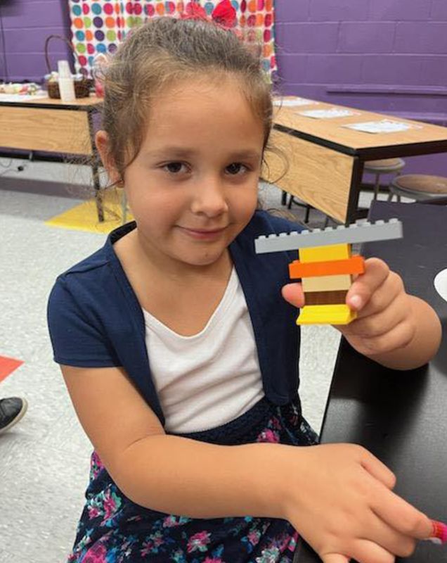 A girl showcasing her Lego build. 